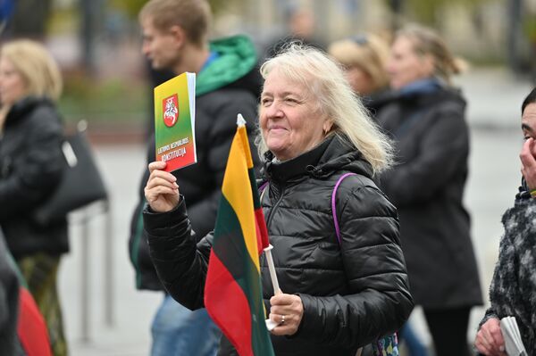 На фото: участница митинга с Конституцией Литвы и национальным флагом. - Sputnik Литва