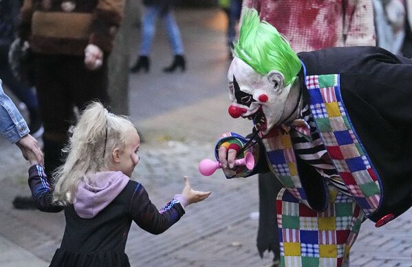 Vyras, persirengęs klounu, žaidžia su maža mergaite prieš kasmetines zombių eitynes ir Helovino paradą Esene, Vokietijoje. - Sputnik Lietuva