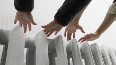 Люди держат руки над батареей, архивное фото