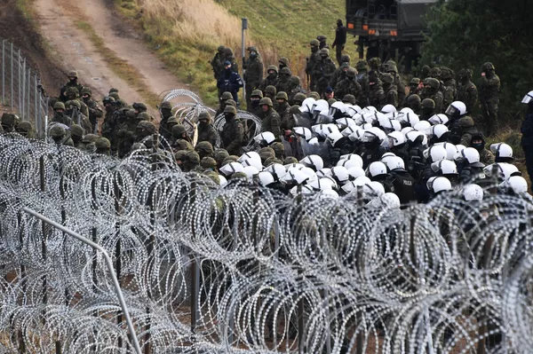 Lenkijos policijos pareigūnai ir kariškiai nelegalių migrantų stovykloje Baltarusijos ir Lenkijos pasienyje. Lapkričio 8 dieną daugiau nei tūkstantis pabėgėlių Baltarusijoje iš Artimųjų Rytų ir Šiaurės Afrikos pajudėjo link Lenkijos sienos. Lenkijos valdžia tai vertina kaip "bandymą masiškai įsiskverbti jėga" ir padidino sienų apsaugą. Lenkijos policijos pareigūnai ir kariškiai nelegalių migrantų stovykloje Baltarusijos ir Lenkijos pasienyje. Lapkričio 8 dieną daugiau nei tūkstantis pabėgėlių Baltarusijoje iš Artimųjų Rytų ir Šiaurės Afrikos pajudėjo link Lenkijos sienos. Lenkijos valdžia tai vertina kaip "bandymą masiškai įsiskverbti jėga" ir padidino sienų apsaugą. - Sputnik Lietuva