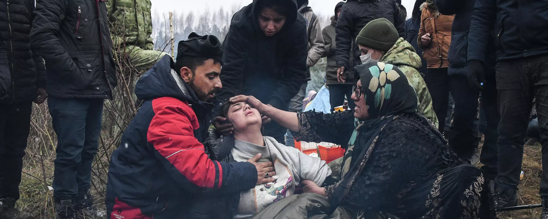 Медицинский работник белорусских погранвойск оказывает помощь женщине в лагере нелегальных мигрантов, архивное фото - Sputnik Lietuva, 1920, 15.11.2021