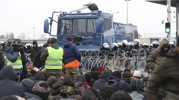Migrantai priešais spygliuotos vielos tvorą Kuznicos kontrolės punkte Baltarusijos ir Lenkijos pasienyje - Sputnik Lietuva