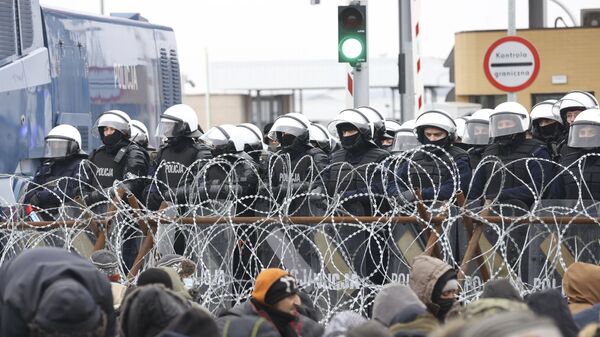 Мигранты перед забором из колючей проволоки на блокпосту «Кузница» на белорусско-польской границе - Sputnik Lietuva