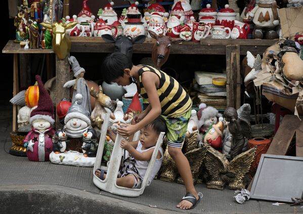Vaikai žaidžia šalia kalėdinių dekoracijų, kurios parduodamos Manilos, Filipinuose, gatvėje. - Sputnik Lietuva