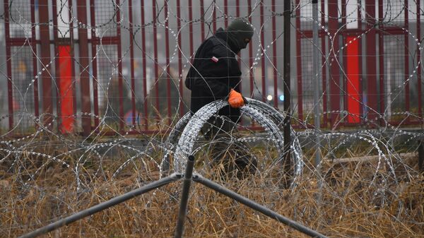 Польский военный монтирует ограждения у лагеря нелегальных мигрантов на белорусско-польской границе - Sputnik Литва