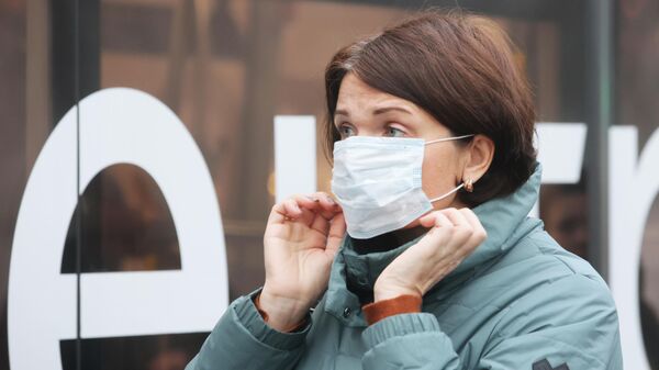 Женщина надевает защитную маску, архивное фото - Sputnik Литва