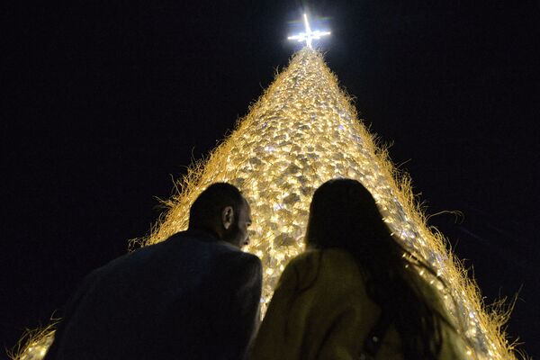 Žmonės renkasi prie milžiniškos tuščiavidurės Kalėdų eglutės, pastatytos Bagdade (Irake), kuriame gyvena daugiausia krikščionių. - Sputnik Lietuva