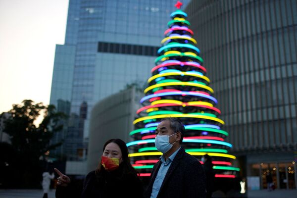 Žmonės stovi prie apšviestos Kalėdų eglutės prie prekybos centro Šanchajuje, Kinijoje. - Sputnik Lietuva