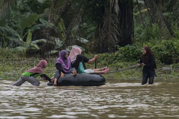 Po smarkių musoninių liūčių Kampung Desa Bakti mieste, Malaizijos Pahango valstijoje, 2021 metų sausio 7 dieną gyventojai plaukia pripučiamomis padangų kameromis potvynio vandens apsemtu keliu. - Sputnik Lietuva