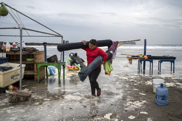 Moteris nuima skėčius nuo paplūdimio, kai stiprios bangos pasiekia pakrantę dėl uragano Grace, kuris pasiekė 2 kategoriją, 2021 metų rugpjūčio 20 dieną Boca del Rio mieste, Verakruse, Meksikoje. - Sputnik Lietuva