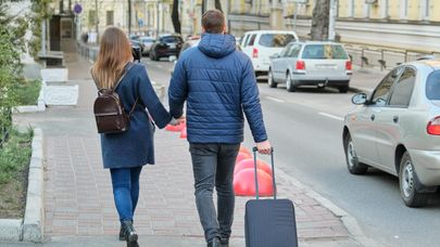Парень и девушка с чемоданом на улице, архивное фото
