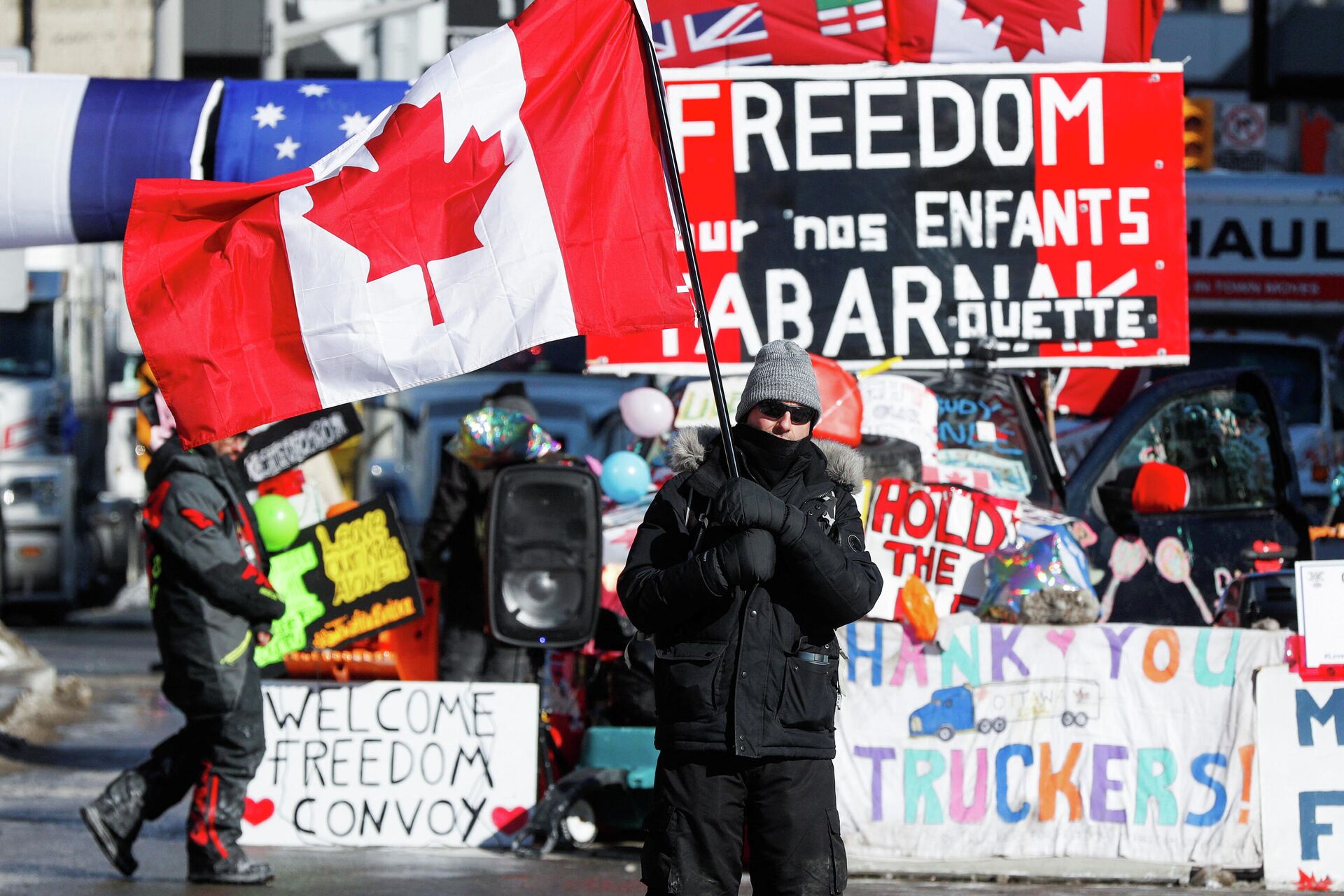 Мужчина с флагом на фоне плакатов во время протеста дальнобойщиков в Канаде - Sputnik Lietuva, 1920, 18.02.2022