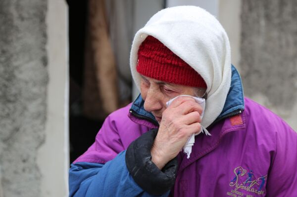 На фото: пожилая женщина плачет около жилого дома в Киевском районе Донецка, разрушенном при обстреле. - Sputnik Литва