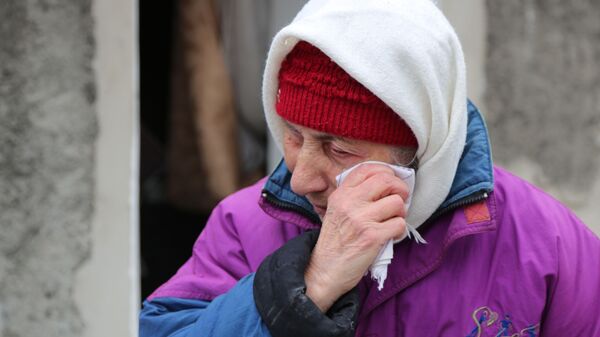 Пожилая женщина плачет около жилого дома в Киевском районе Донецка, разрушенном в результате обстрела - Sputnik Литва