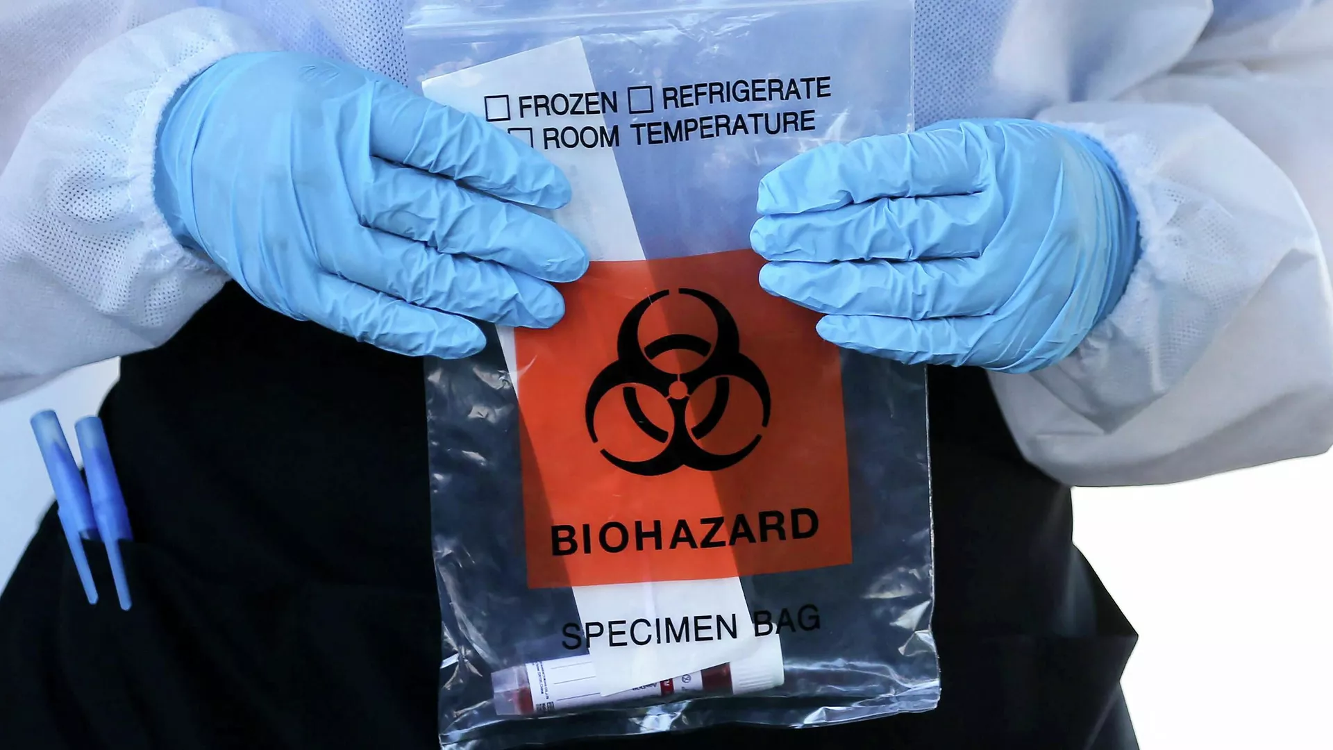 Medicinos darbuotojas neša maišelį su biologiškai pavojingomis medžiagomis