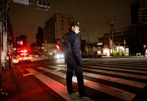 Po žemės drebėjimo Tokijuje, Japonijoje, policijos pareigūnas bando kontroliuoti eismą gatvėje. - Sputnik Lietuva