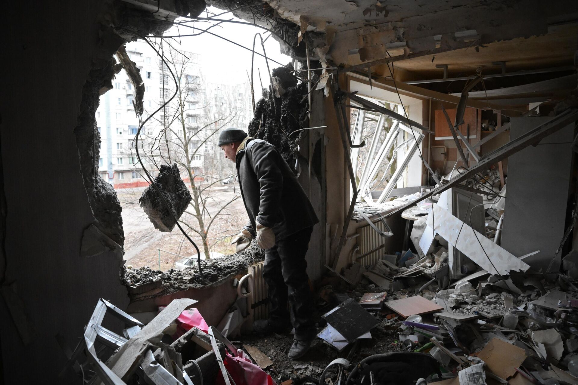Мужчина в квартире, разрушенной в результате прямого попадания снаряда в жилой дом в Горловке - Sputnik Lietuva, 1920, 23.03.2022