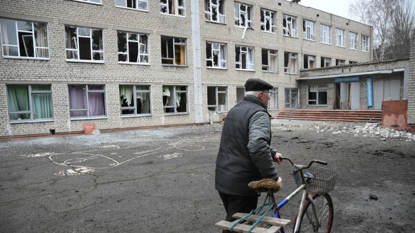 Senyvo amžiaus vyras prie apšaudymo apgadintos mokyklos pastato Gorlovkoje - Sputnik Lietuva