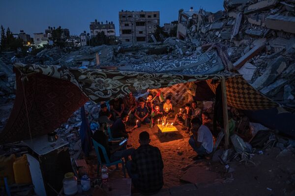 Palestinos vaikų Gazoje nuotrauka, kurią užfiksavo palestiniečių fotografė Fatima Shbair, &quot;ASIA Singles&quot; nugalėtoja. Palestinos vaikai laiko žvakes per mitingą tarp Izraelio antskrydžių sugriautų namų griuvėsių, Beit Lahia Šiaurės Gazos ruože. Gazos gyventojai grįžo į apgadintus ir sugriautus namus, kai atrodė, kad Izraelio ir &quot;Hamas&quot; paliaubos tęsiasi. Paliaubos užbaigė vienuolika dienų trukusias kovas, per kurias žuvo daugiau nei 250 palestiniečių, daugelis iš jų – moterys ir vaikai. Konfliktas prasidėjo gegužės 10 d., kilus įtampai Rytų Jeruzalėje ir susirėmimams Al Aksos mečetės teritorijoje. - Sputnik Lietuva