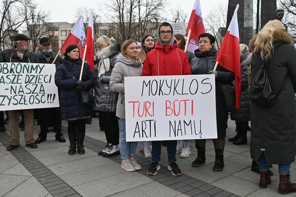 Участник акции держит в руках плакат с надписью: &quot;Школы должны быть рядом с домом&quot;. - Sputnik Литва