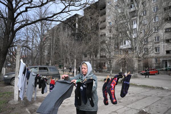 На фото: женщина вешает белье во дворе жилого дома в Мариуполе. - Sputnik Литва