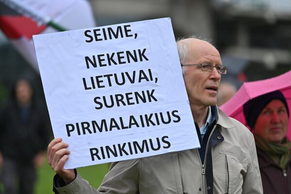 На фото: участник митинга держит плакат &quot;Сейм, не причиняй вред Литве, собери досрочные выборы&quot;. - Sputnik Литва