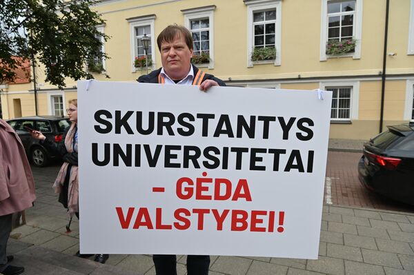Участник акции протеста держит плакат с надписью: &quot;Бедствующие университеты — позор государству!&quot; - Sputnik Литва