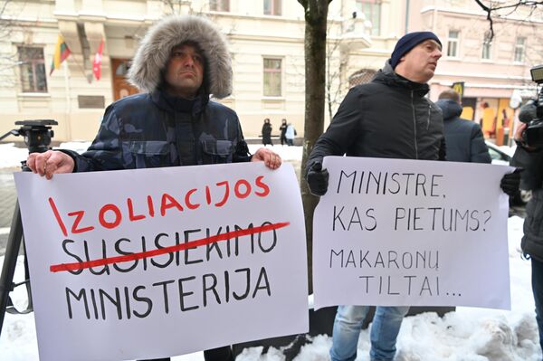 На фото: протестующие у Министерства транспорта в Вильнюсе держат плакаты, на одном из которых надпись &quot;Министерство транспорта&quot; исправлена на &quot;Министерство изоляции&quot;. - Sputnik Литва