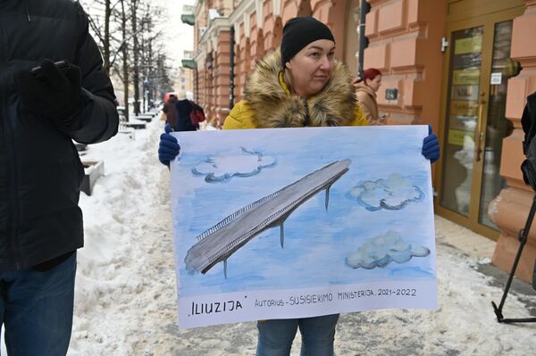 На фото: участница акции держит плакат, на котором нарисован мост в облаках с подписью &quot;Иллюзия&quot; — автор Министерство транспорта&quot;. - Sputnik Литва