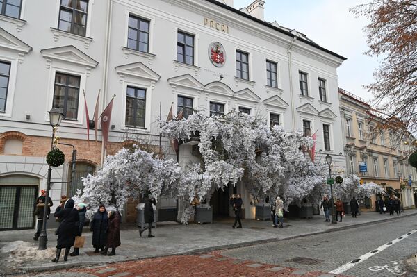 На фото: прохожие возле празднично украшенного входа в гостиницу Pacai в Вильнюсе. - Sputnik Литва
