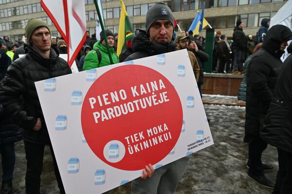 На фото участник акции протеста держит плаката, на котором в сравнении показано, какова цена на молоко в магазине (85 центов), и сколько от этой цены достается фермеру (15 центов). - Sputnik Литва