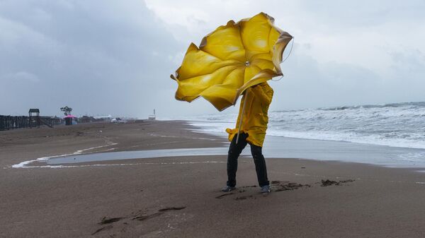 Мужчина с зонтом на пляже в ветреную погоду - Sputnik Литва