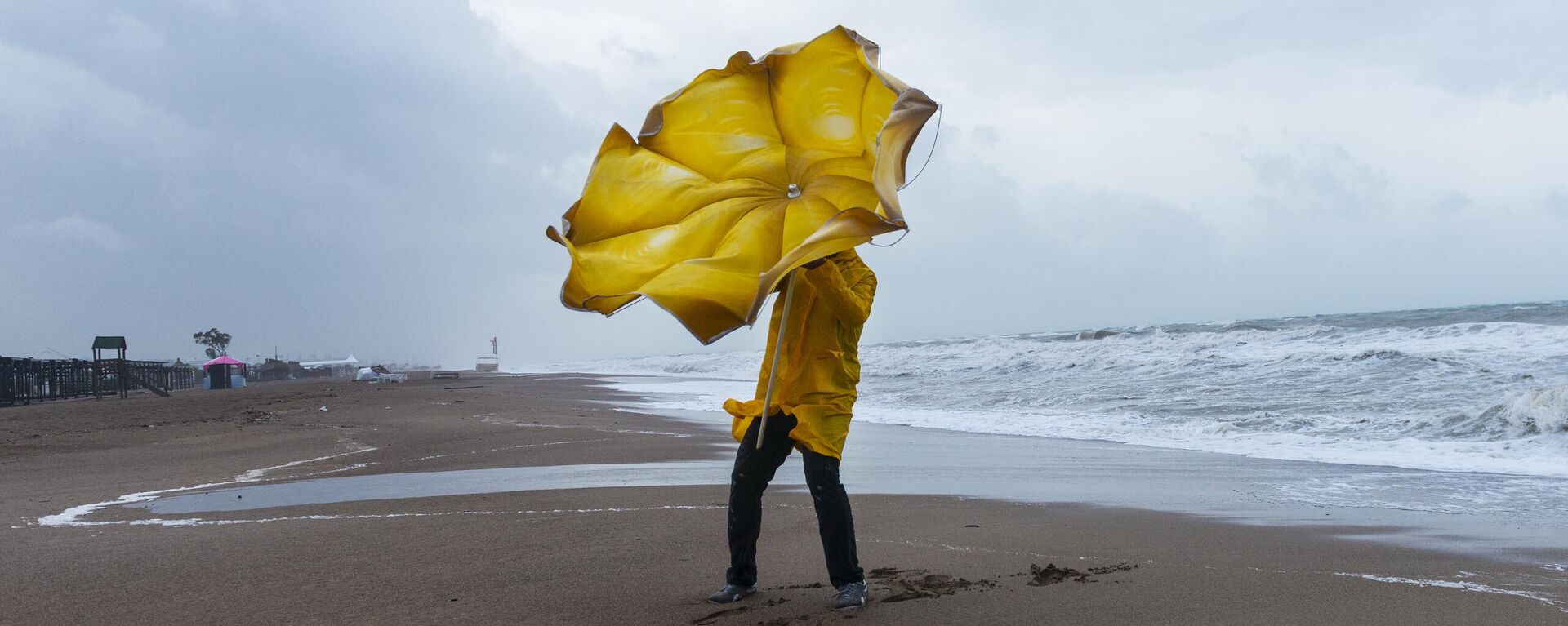 Мужчина с зонтом на пляже в ветреную погоду - Sputnik Литва, 1920, 06.11.2023