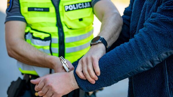 Литовский полицейский надевает наручники на мужчину, архивное фото - Sputnik Литва