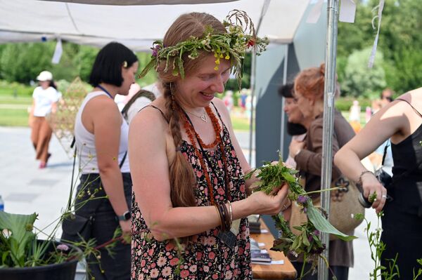 На фото: женщина плетет венок из цветов и трав. - Sputnik Литва
