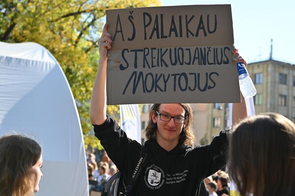 На фото: юноша в руках держит плакат с надписью: &quot;Я поддерживаю бастующих учителей&quot;. - Sputnik Литва