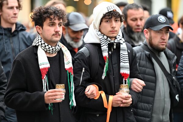 Участники процессии несли в руках свечи в память о погибших в Палестине, также у многих на запястье были повязаны оранжевые ленточки. - Sputnik Литва