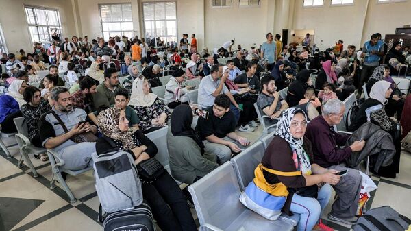 Люди сидят в зоне ожидания на пограничном переходе Рафах на юге сектора Газа - Sputnik Литва