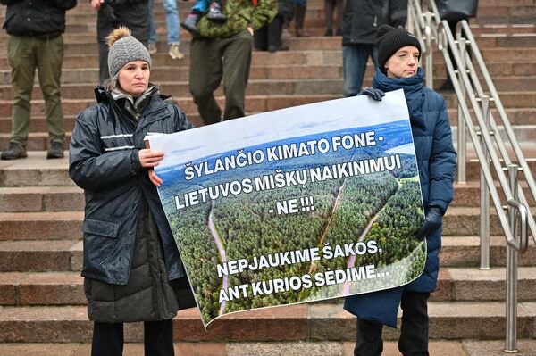На фото: участники акции держат плакат с надписью: &quot;На фоне потепления климата — уничтожению литовских лесов — НЕТ!!! Давайте не будем рубить сук, на котором сидим&quot;. - Sputnik Литва