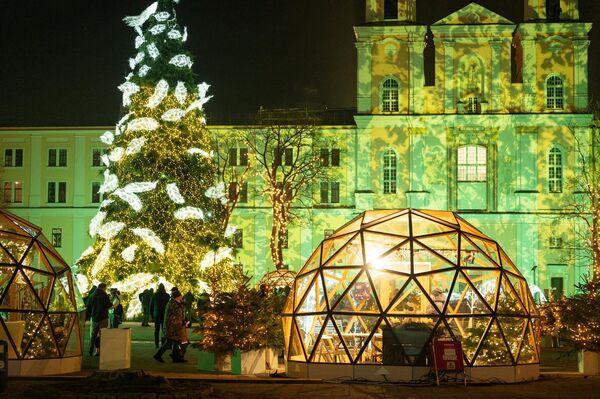 В этом году в новогодних декорациях задействовали проектор, превративший фасады зданий вокруг елки в интерактивный экран. - Sputnik Литва
