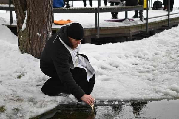 На фото: священник окунает крест в воду. - Sputnik Литва
