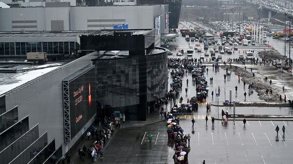 Люди стоят в очереди к стихийному мемориалу возле Крокус Сити Холла в память о жертвах теракта. - Sputnik Литва