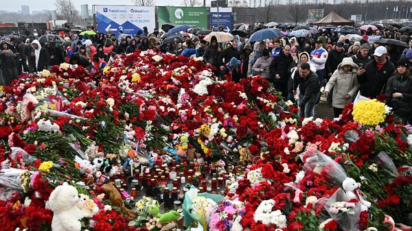 Люди возлагают цветы к стихийному мемориалу возле Крокус Сити Холла в память о жертвах теракта - Sputnik Литва