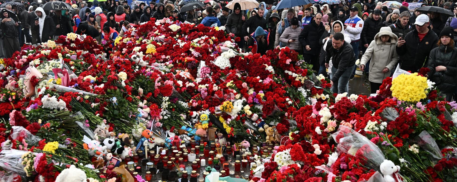 Люди возлагают цветы к стихийному мемориалу возле Крокус Сити Холла в память о жертвах теракта - Sputnik Литва, 1920, 24.03.2024
