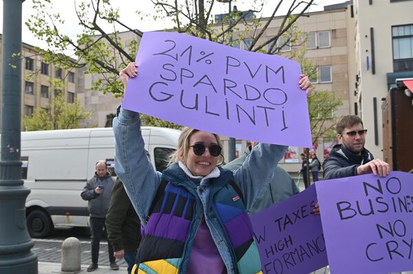На фото: участница акции держит плакат с надписью: &quot;НДС в размере 21 процента — это удар по лежачему&quot;. - Sputnik Литва