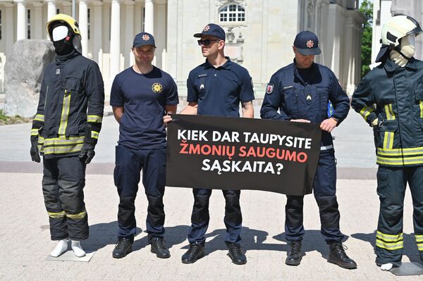 На фото: участники пикета держат плакат с надписью: &quot;Как долго еще будете экономить за счет безопасности людей?&quot; - Sputnik Литва