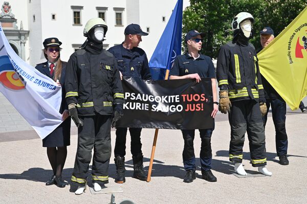 На фото: участники пикета держат плакат с надписью: &quot;Защитите тех, кто бережет вас&quot;. - Sputnik Литва