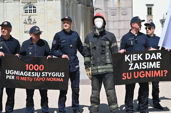 На фото: участники пикета держат плакаты с надписями: &quot;Нехватка 1000 пожарных за 11 лет стала нормой&quot;, &quot;Сколько еще будем играть с огнем?&quot; - Sputnik Литва