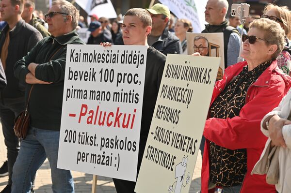 На фото: участники акции протеста держат плакаты с надписями: &quot;Когда налоги вырастают почти на сто процентов, первая моя мысль — кредит в 200 тысяч евро для [премьера Литвы Гинтаутаса] Палуцкаса слишком мало&quot;, &quot;Я был фермером, после налоговой реформы — должник в статистических данных&quot;. - Sputnik Литва