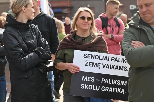 На фото: участница акции протеста держит плакат с надписью: "Деды оставили детям землю. Мы оставим график задолженностей". На фото: участница акции протеста держит плакат с надписью: "Деды оставили детям землю. Мы оставим график задолженностей". - Sputnik Литва